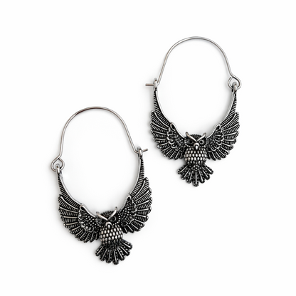 Pair of silver owl-shaped earrings on a white background