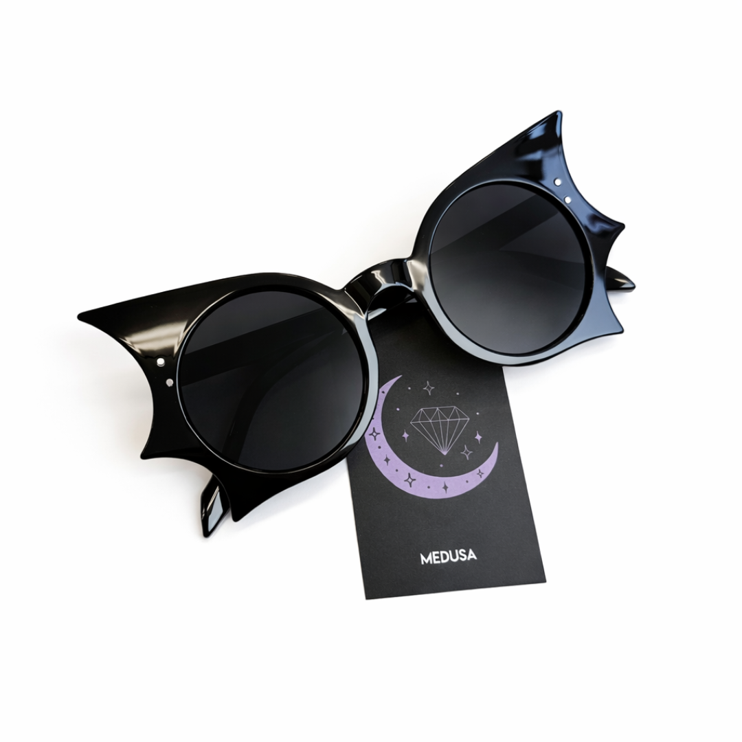 Black cat-eye sunglasses with a branded card on a white background