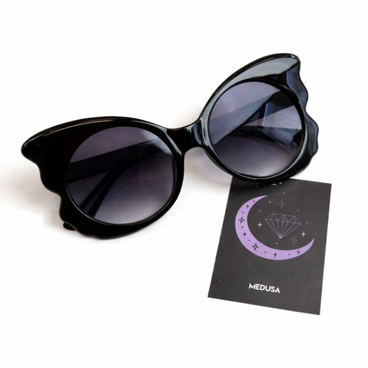 Black cat-eye sunglasses with a branded card on a white background
