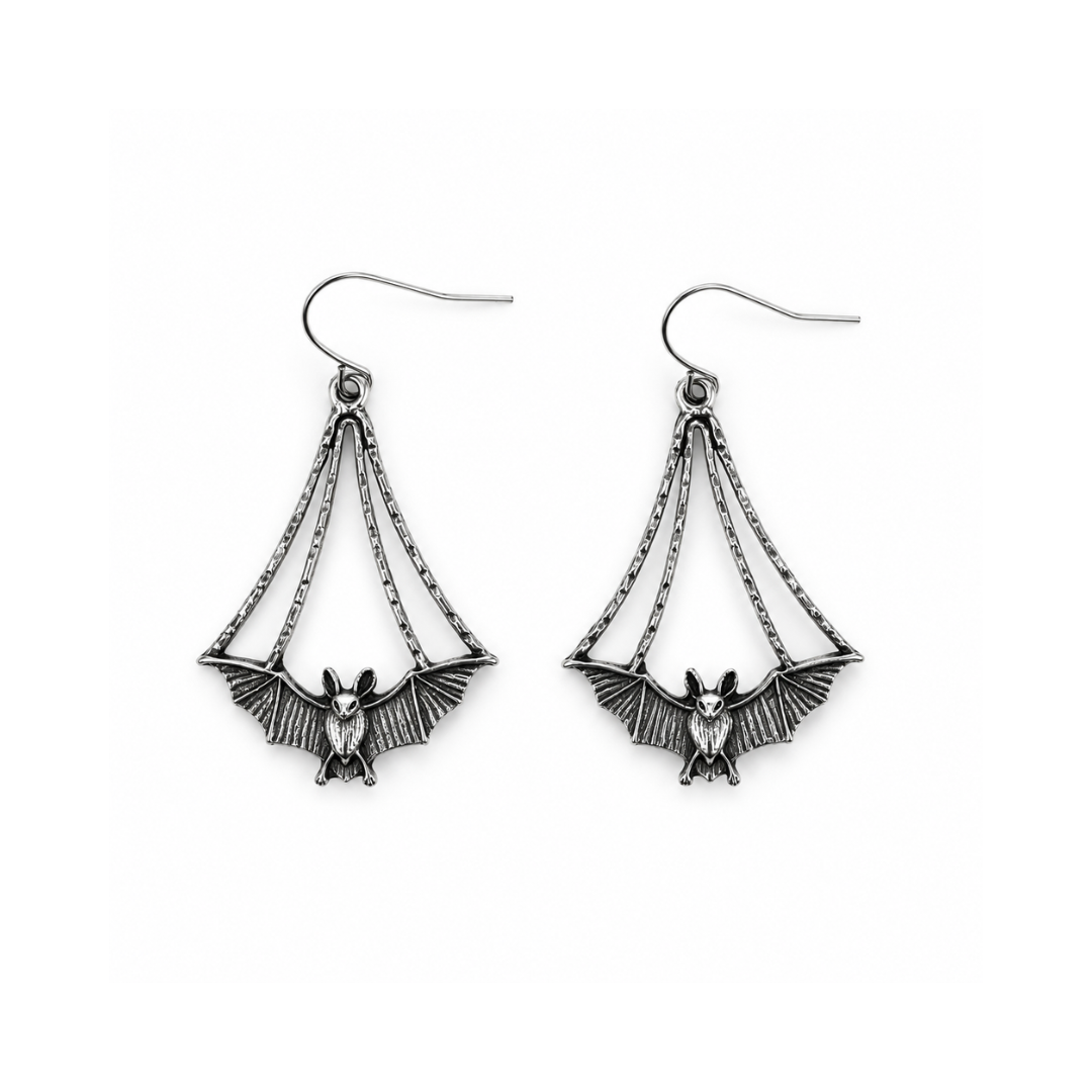 A pair of silver-toned dangle earrings featuring a bat motif with wings spread, suspended by chain-like details from fishhook wires, shown on a plain white background.