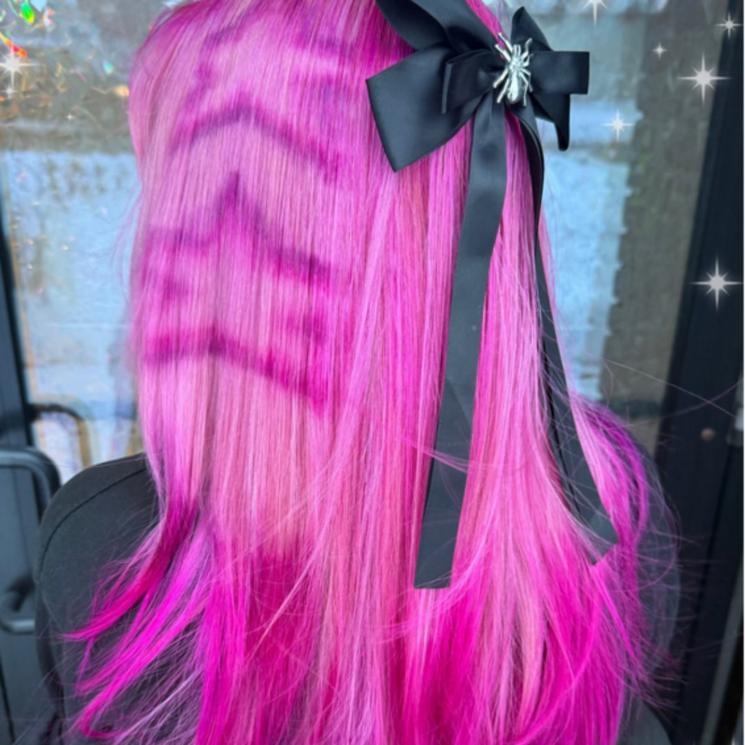 Person with bright pink hair styled in a high ponytail with a black bow.