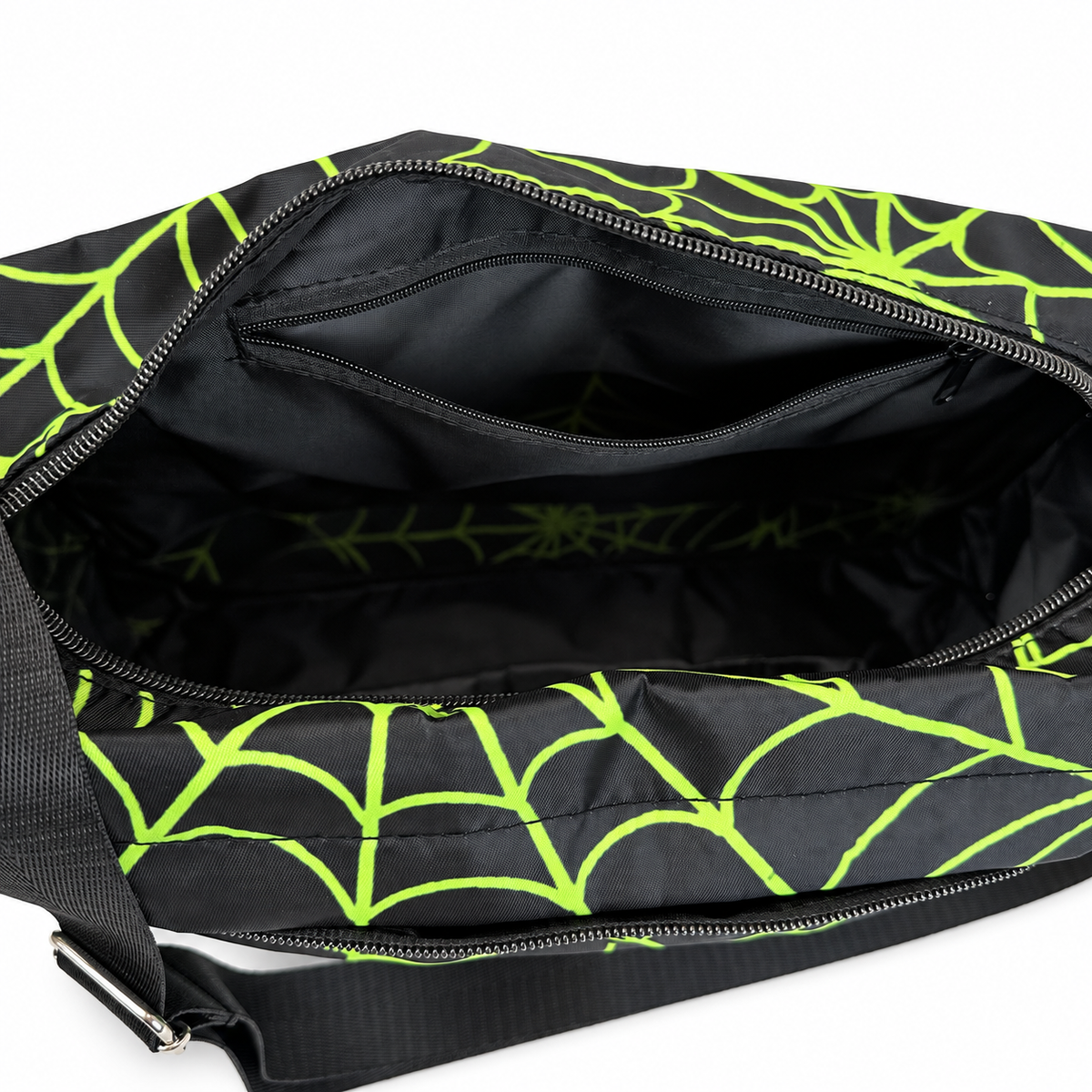 Close-up of the interior of a black bag with a bright neon green spiderweb pattern, showing a zippered compartment and inner pocket.