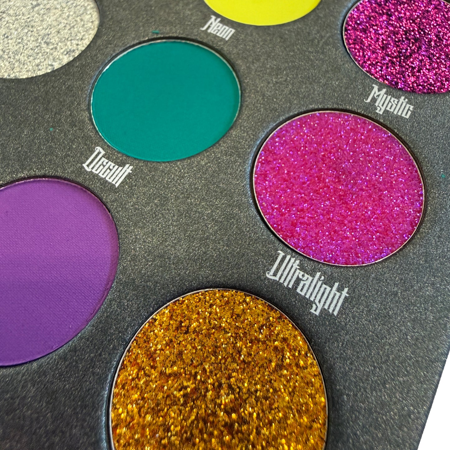 Makeup palette with colorful eyeshadows labeled 'Decadent', 'Mystic', 'Ultralight', and 'Neon'.