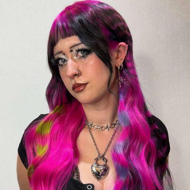 Instagram creator Person with vibrant pink and purple hair against a neutral background