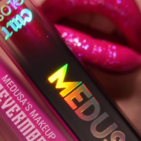 Close-up of a red lip with glitter and a 'Medusa's Makeup' product.