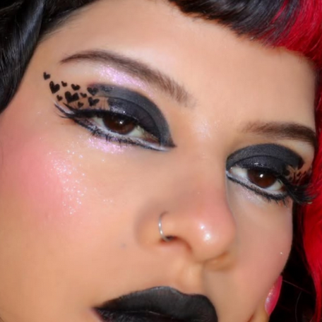Close-up of a person with dramatic makeup, including black eyeliner and red hair peeking out.