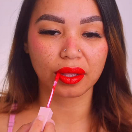 Woman applying red lipstick with a close-up focus on her lips.