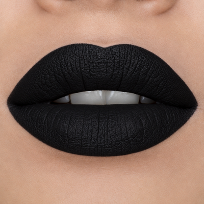 Close-up of a person's lips wearing a matte, ultra-deep black lipstick with a textured finish.