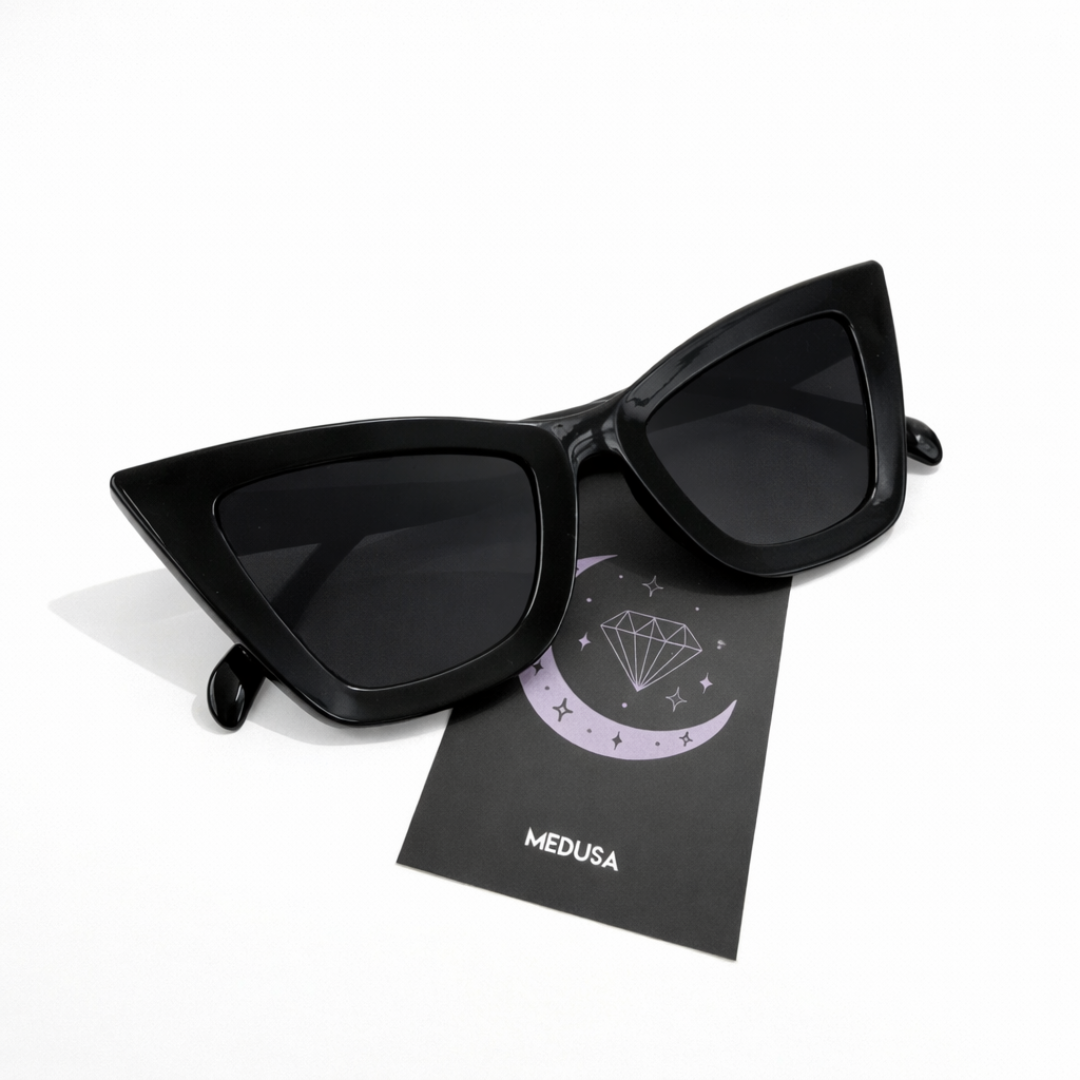 Black cat-eye sunglasses on a black card with 'Medusa' branding on a white background