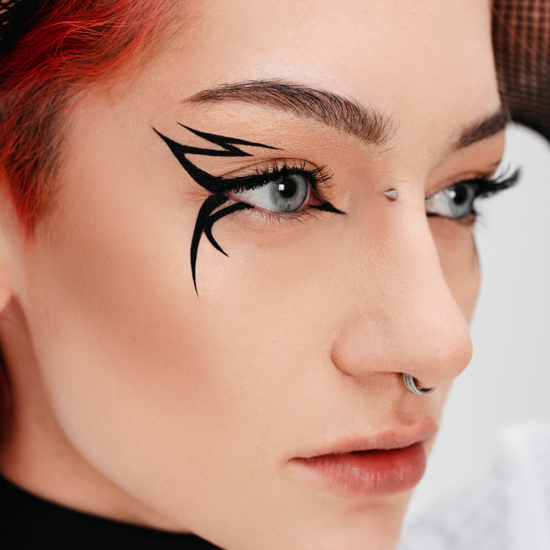 Close-up of a person with stylized black eyeliner and red hair.