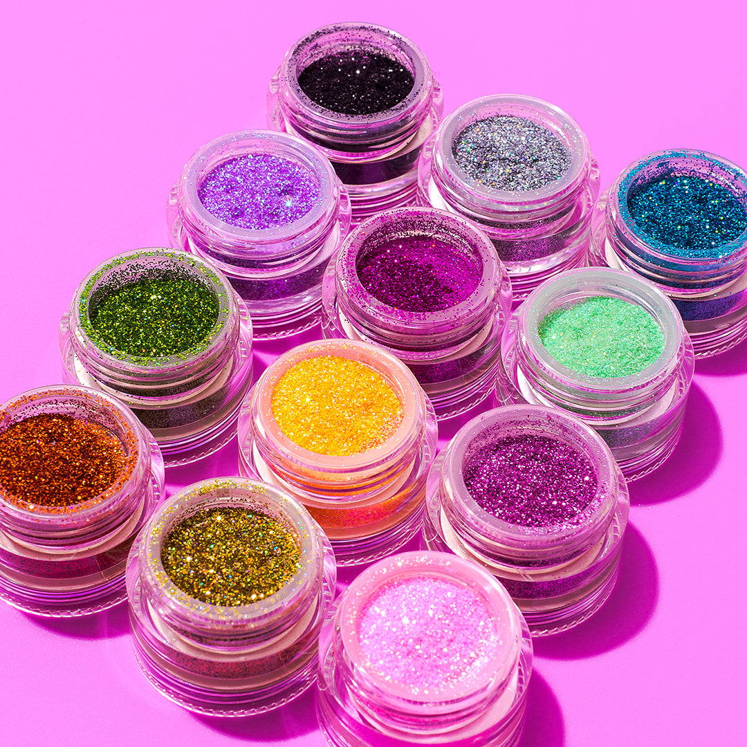 Various colors of Medusa's Makeup glitter eyeshadow natural glitter makeup pots on a pink background