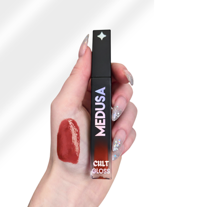Lip gloss with 'Medusa' branding held by a hand against a white background