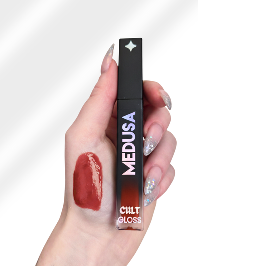 Lip gloss with 'Medusa' branding held by a hand against a white background