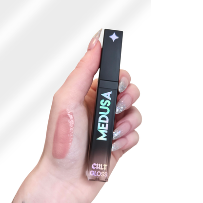 Hand holding a 'MEDUSA' lip gloss with a visible color swatch on the skin.