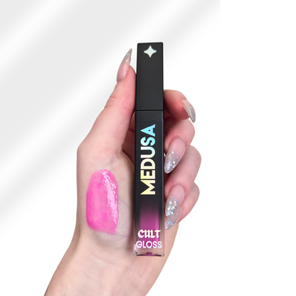 Hand holding a Cult Beauty Medusa lip gloss with pink lip color on a white background
