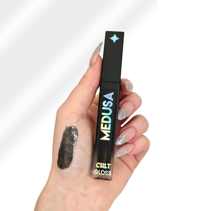 Hand holding a Cult Cosmetics Medusa lip gloss with a swatch on the palm against a white background