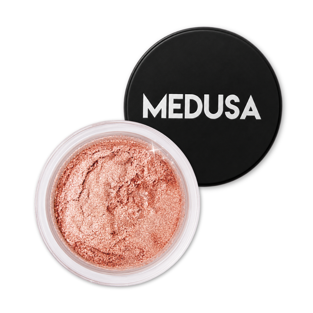 Rose gold makeup powder in a clear container with 'MEDUSA' lid on a white background