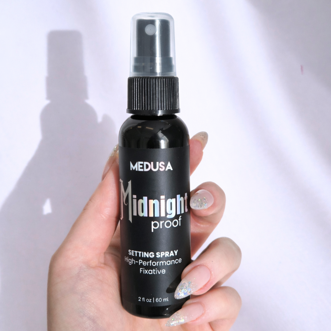 Hand holding a black spray bottle labeled 'Medusa Midnight Proof' against a white background