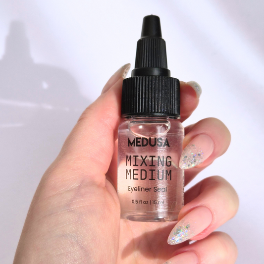 Hand holding a bottle of Medusa Mixing Medium against a white background