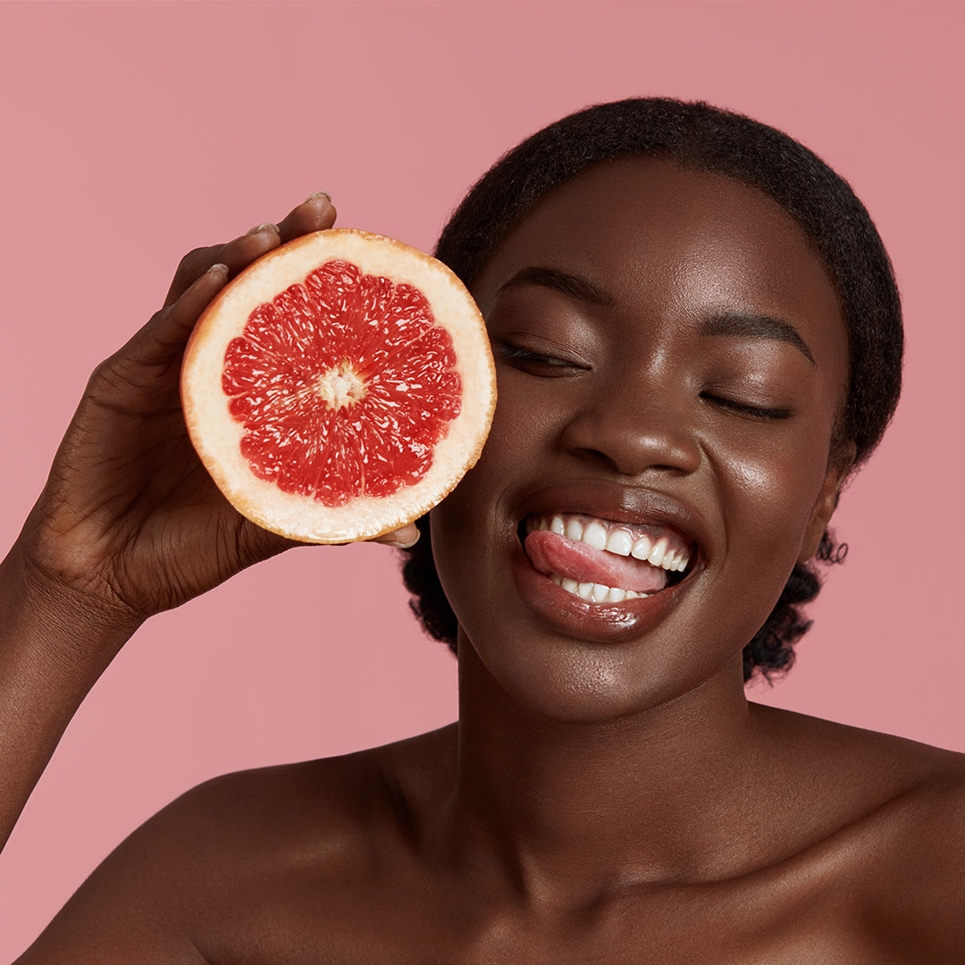 model holding a slice of grapefruit. Model has beautiful skin portraying the useage of Afterglow facial serum.
