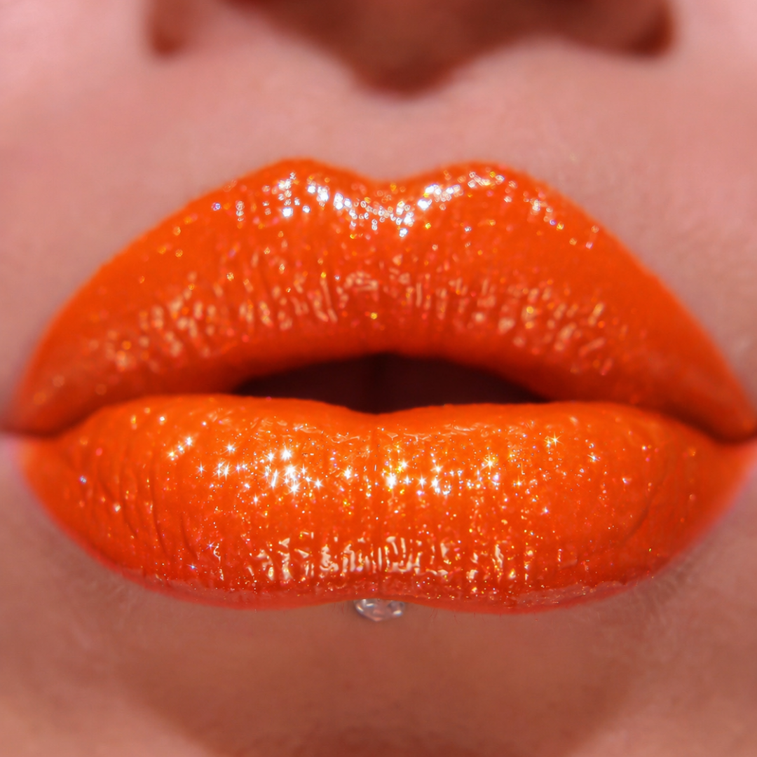 Close-up of bright orange glossy lipstick on lips