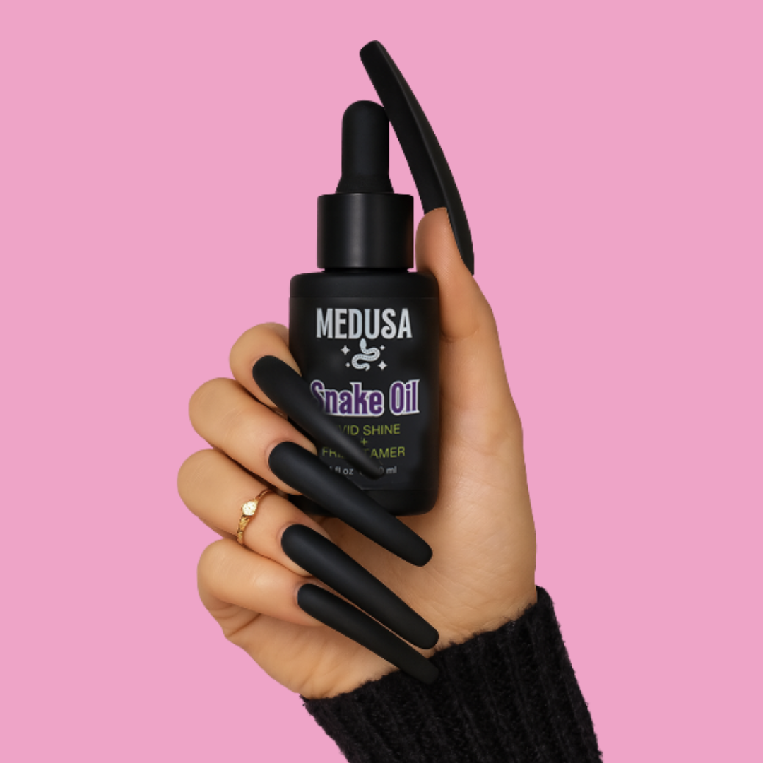 Hand holding a black bottle labeled 'Medusa Snake Oil' against a pink background