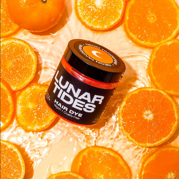 Lunar Tides Hair Dye - Neon Tangerine jar in a scenery on ornage slices